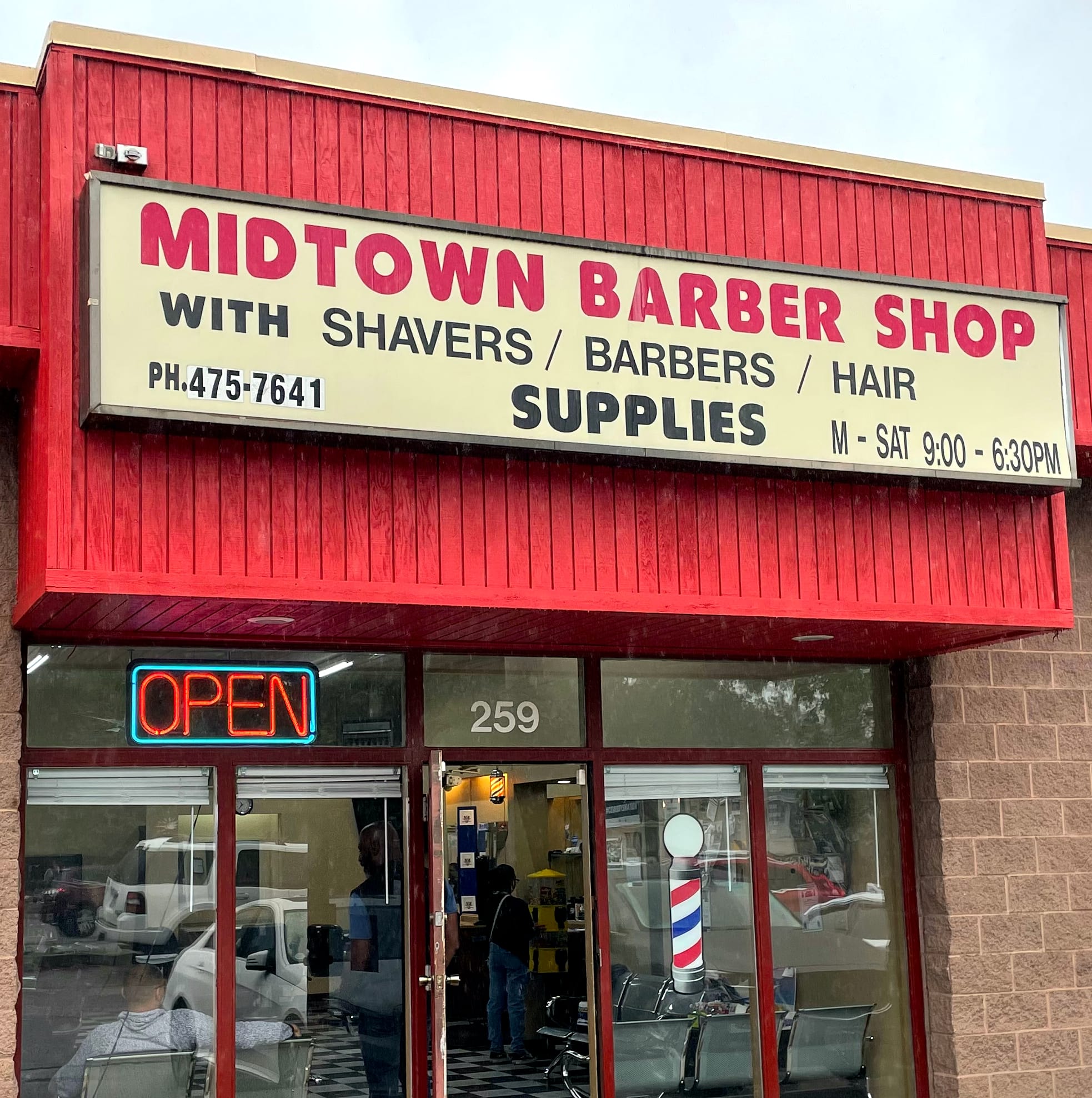 Storefront: red roof, Midtown Barber Shop sign. In window is an "Open" sign and decal of barber pole.