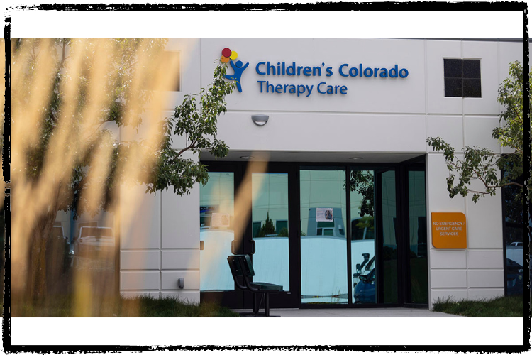 A white building with large, sliding, glass entry doors. Children's Hospital logo abo
