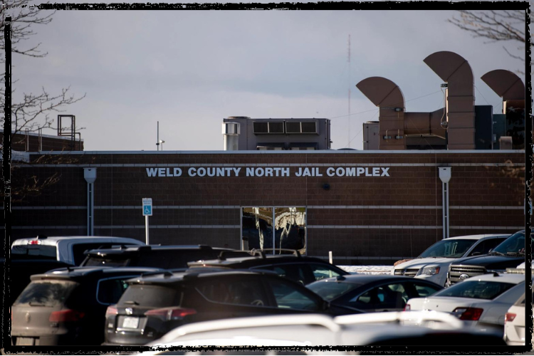 Red brick building w/tall exhaust manifolds. Silver letters say "Weld County North Jail Complex"