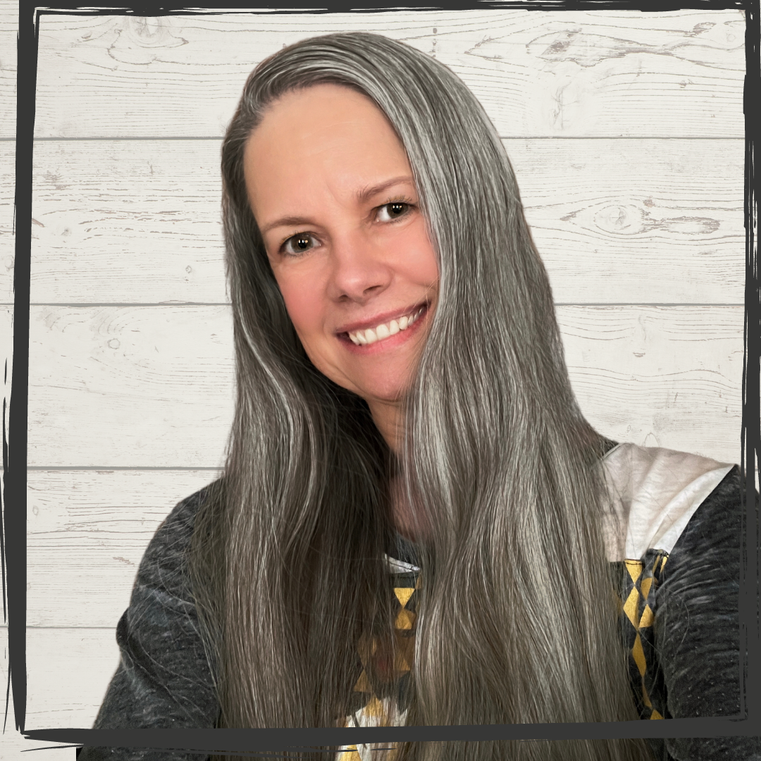 A light Indigenous woman with long, silver black hair smiles