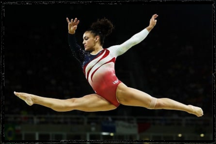 Photo of Laurie Hernandez leaping with 1 leg in front and other in back and arms upraised; she wears a Team USA leotard