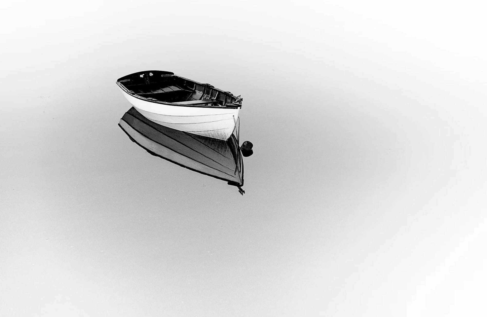 B&w photo of an empty rowboat adrift