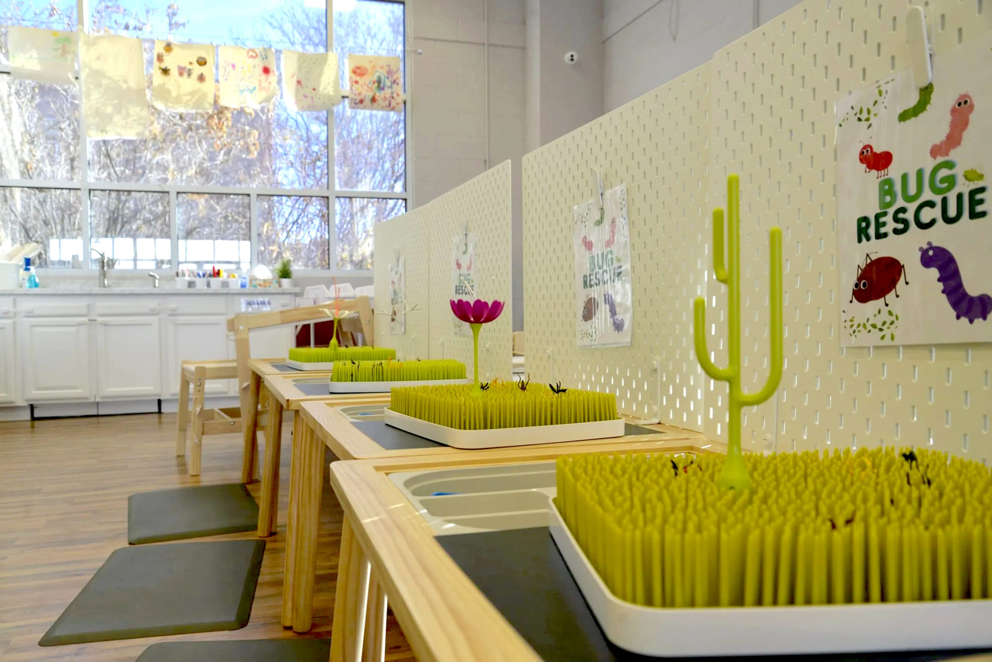 Photo of 3 tables with trays of rubber whiskers and bins of "insects" to place in the "grass."