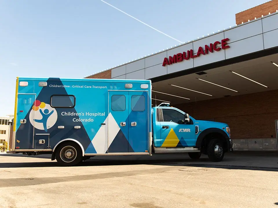 Photo of a blue & gold ambulance with the Children's Hospital Colorado pulling into an Emergency Dept bay