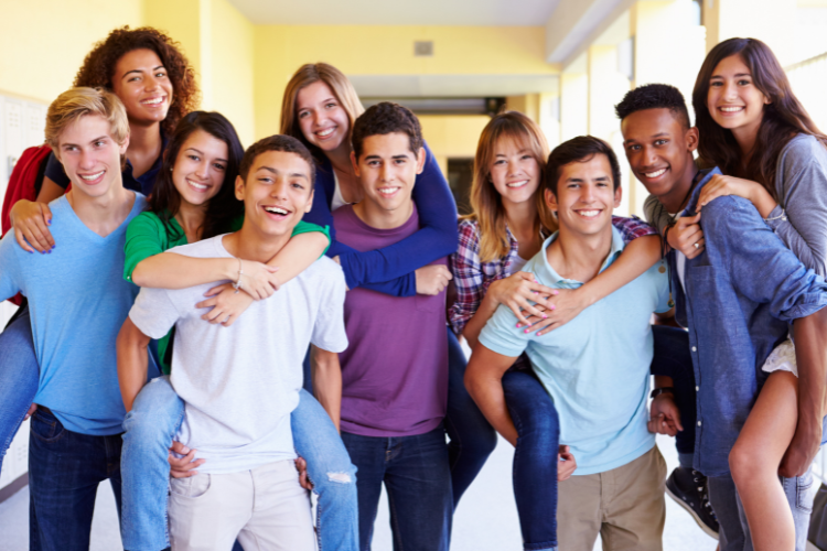 A group of 10 diverse high school students smiling in a school hallway