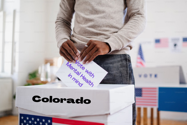 Person places a ballot in a ballot box. Ballot: "Vote with Mental Health in Mind." Box is labled "Colorado"