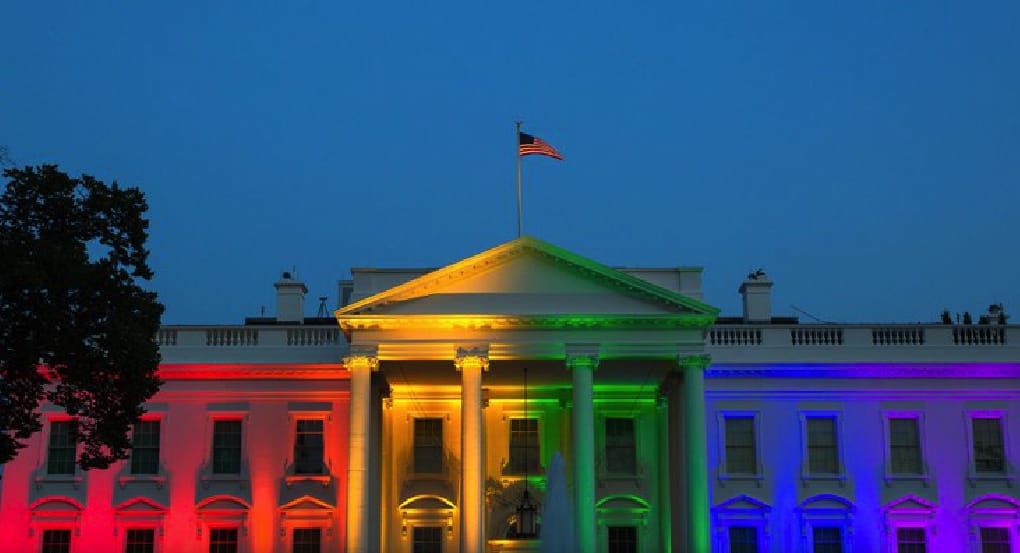 Photo of the White House with rainbow lights reflecting off the facade.