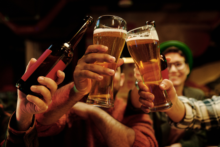 A group of people clink beer glasses and bottles in a toast