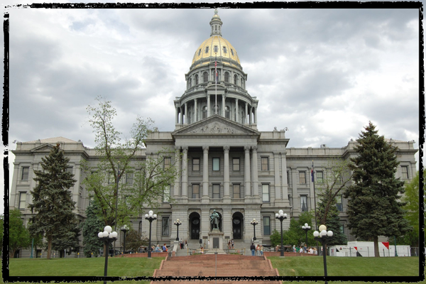 The gold dome of the Colorado state capitol building appears in this front elevation view with clouds in the background