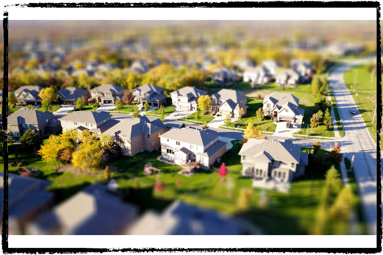 Stylized photo of a neighborhood with large, 2-story homes and green grass near a street