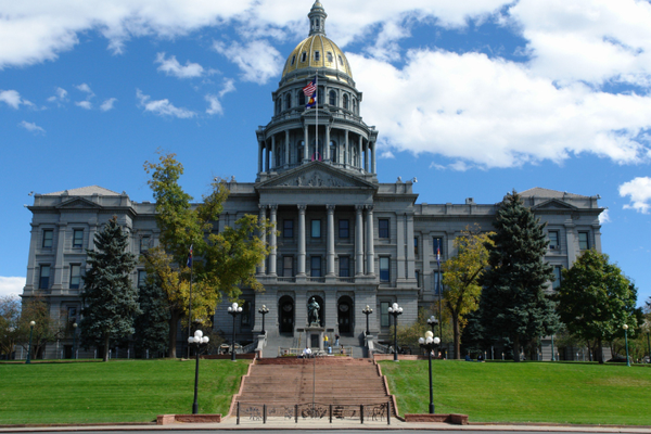 Photo of the Colorado State Capitol with clouds in a sunny sky and green grass