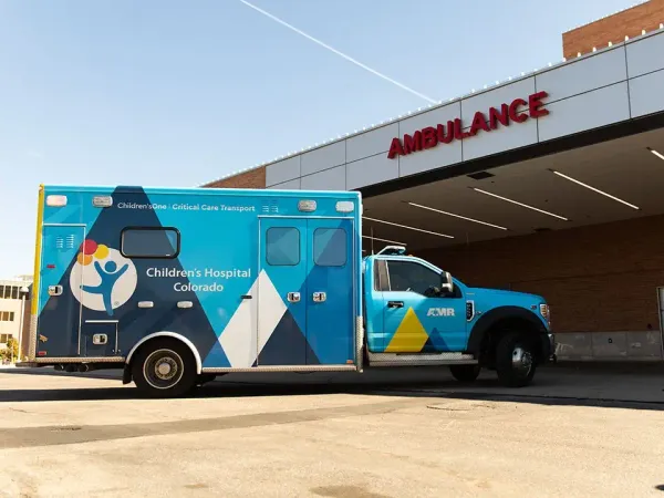 Photo of a blue & gold ambulance with the Children's Hospital Colorado pulling into an Emergency Dept bay