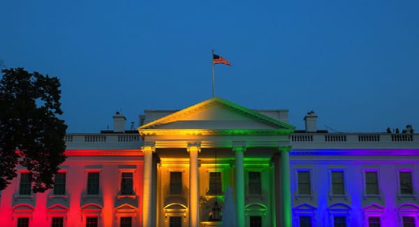 Photo of the White House with rainbow lights reflecting off the facade.
