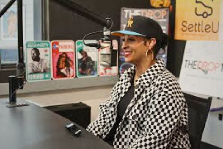 A Black woman in a Rockies ballcap wears a b&w checkered shirt and smiles