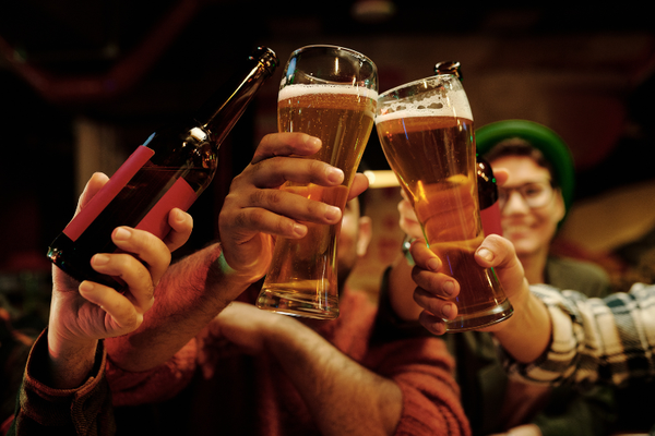 A group of people clink beer glasses and bottles in a toast